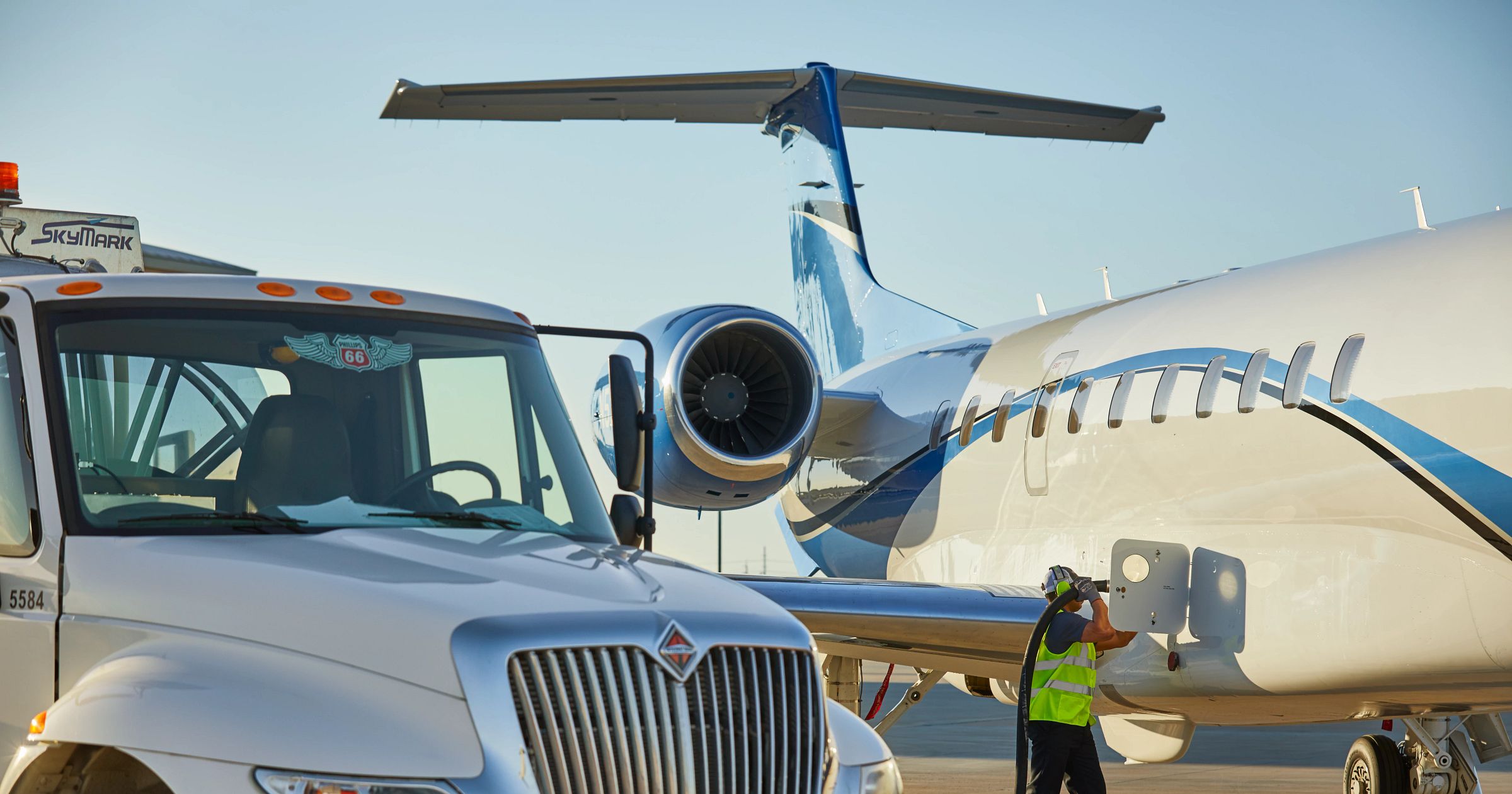 A fuel truck from Skymark refueling a private jet on an airfield, illustrating the process of contract fuel for FBOs and aircraft.